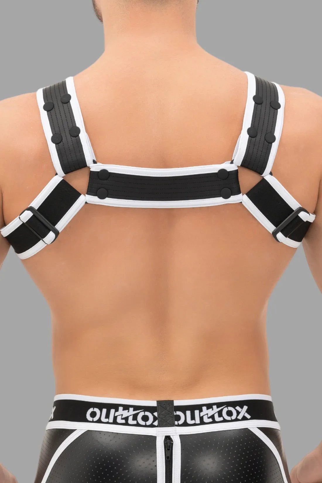 Outtox Body Harness by Maskulo, black and white with adjustable snaps and integrated cockring for a push-up effect. Polyester blend.
